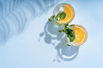 Two glasses of summer orange cocktails with citrus fruits on a blue background. Lemonade,...