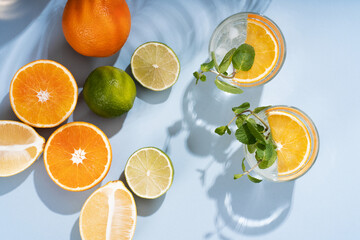 Summer orange cocktails with citrus fruits on blue background. Hard seltzer, lemonade, refreshing...
