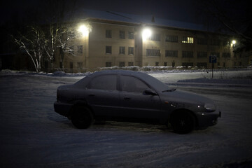 Car in parking lot in winter at night. Transport in snow in dark.