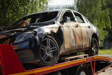 Burned-out car. Evacuation of vehicles after accident. Transportation of machine. Burnt metal.