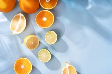 Foto op Plexiglas Summer orange cocktails with citrus fruits on blue background. Hard seltzer, lemonade, refreshing drinks, low alcohol mocktails, summer party concept. Trendy palm leaf shadow and sunlight, sun. © Anna