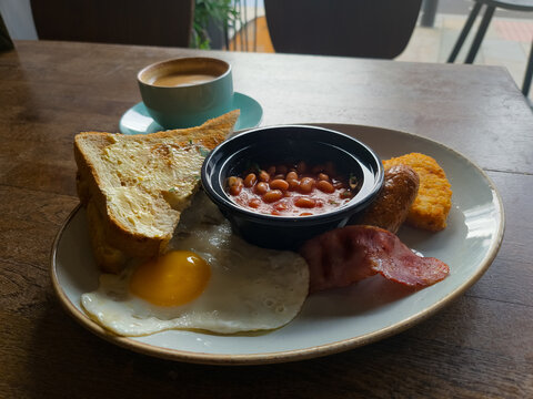 Full English breakfast with beans and sausage served on wooden table