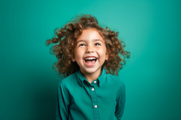 Joyful Child with Curly Hair Laughing on Emerald Green Background