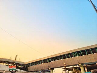From below of skywalk outside railroad station under orange sky at sunset in Mumbai