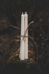 Three white candles tied with twine on a background of nature