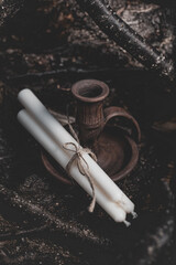 Three white candles tied with twine next to a wooden candlestick