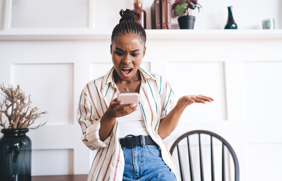 Shocked black woman reading news on smartphone