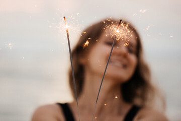 Beautiful woman with sparklers on the beach