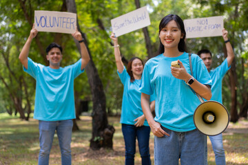 Happy young Asian students diverse volunteers hold a campaign sign for cleaning in the park, The...