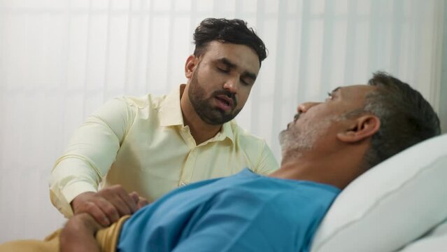 worried Indian son consoling elderly admitted father at hospital ward - concept of parental inspiration, emotional bonding and family bonding