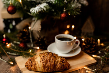 Espresso coffee, croissant near christmas tree on table. Coffee break