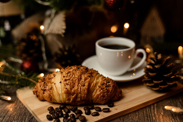 Espresso coffee, croissant near christmas tree on table. Coffee break