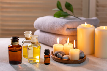 Beauty spa treatment items on white wooden table. Candles, stones, essential oils and towels. Cosy...