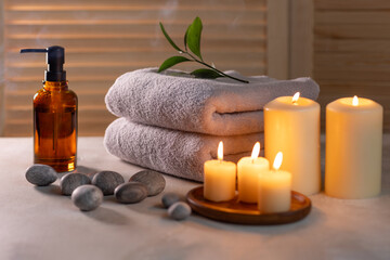 Obraz na płótnie Canvas Beauty spa treatment items on white wooden table. Candles, stones, essential oils and towels. Cosy bath.