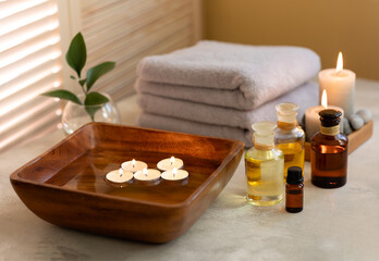 Fototapeta na wymiar Beauty spa treatment items on white wooden table. Candles, stones, essential oils and towels. Cosy bath.
