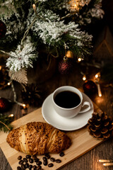 Obraz na płótnie Canvas Espresso coffee, croissant near christmas tree on table. Coffee break
