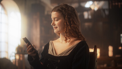 Innovation Concept: Beautiful Female in Medieval Clothes Using Smartphone Indoors. Historical...