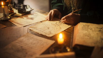 Close Up on Old Renaissance Male Hand Using Ink and Quill to Draw a Blueprint for a New Invention....
