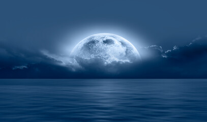 Night sky with blue moon in the clouds over the calm blue sea, many sytars in the background  "Elements of this image furnished by NASA