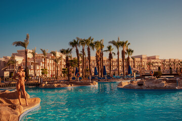 A girl in a swimsuit poses near the pool overlooking the hotel complex in Hurghada - obrazy, fototapety, plakaty
