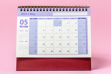 Desk calendar for May 2024 on a pink background.