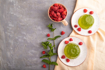 Mint and raspberry green jelly on gray concrete and orange linen textile. top view, copy space.