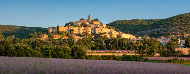 The village of Banon in Provence with clary sage fields at sunrise in summer. Hilltop village in...