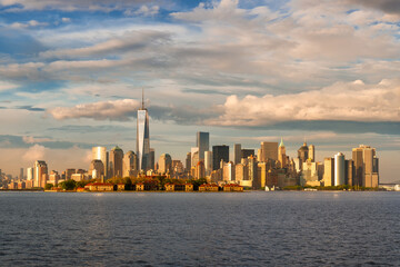 Fototapeta premium New York Harbor view of Lower Manhattan Financial District skyscrapers and Ellis Island bathed in late afternoon sunlight. New York City skyline