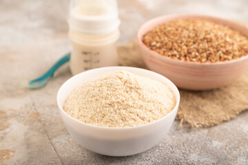 Powdered milk and buckwheat baby food mix, on brown concrete, side view, selective focus