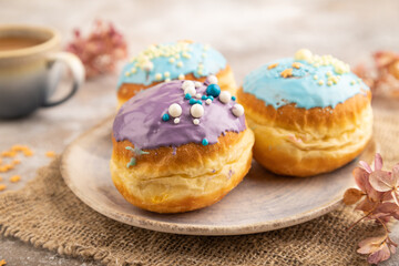 Purple and blue glazed donut and cup of coffee on brown concrete, side view, selective focus.