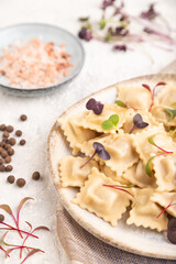 Dumplings with pepper, herbs, microgreen on gray concrete. Side view, selective focus.