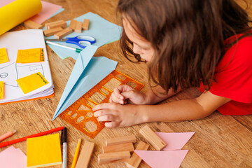 child makes a model of an airplane out of paper. the boy is engaged with scissors and paper. the...