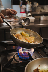 Close up of chef cooking rigatoni pasta on a metal pan at an italian restaurant