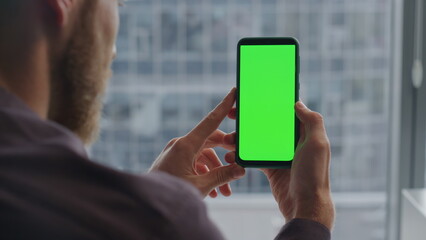 Bearded guy hands using greenscreen phone indoors. Man checking mockup screen
