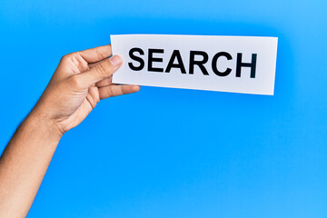 Hand of caucasian man holding paper with search word over isolated blue background