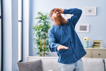 Young redhead man suffering dizzy standing at home
