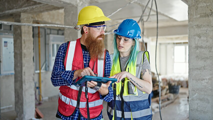 Man and woman builders using touchpad working at construction site