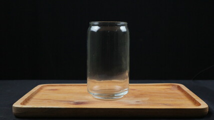 Empty glass cups and straws on wooden tray isolated on dark background