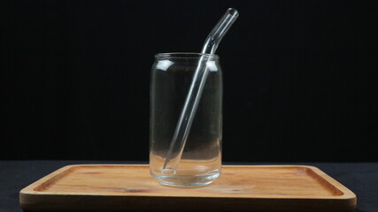 Empty glass cups and straws on wooden tray isolated on dark background