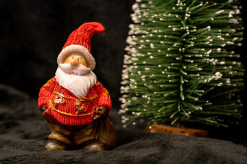 Weihnachtsmann neben verschneitem Tannenbaum, schwarzer Hintergrund