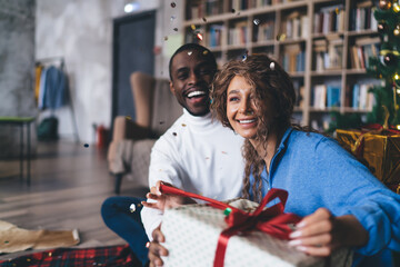 Exuberant interracial couple unwrapping a Christmas gift