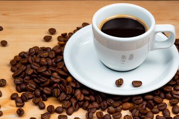 Cup of coffee and coffee beans on a wooden table.