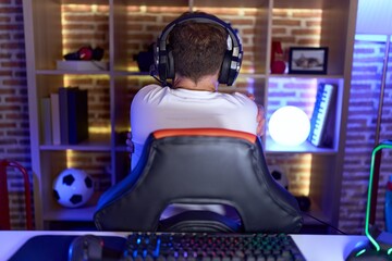 Middle age man with beard playing video games wearing headphones hugging oneself happy and positive...
