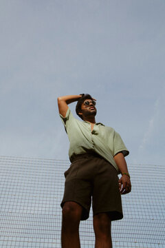 Young Indian man in trendy outfit posing at the park looking up