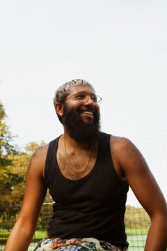 Trendy guy at the park smiling looking away from camera