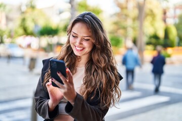 Young beautiful hispanic woman smiling confident using smartphone at street