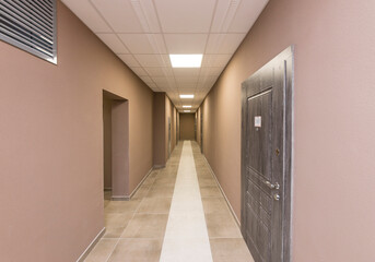 Corridor of a new residential complex, corridor with doors on the left and right, ceiling lighting,...