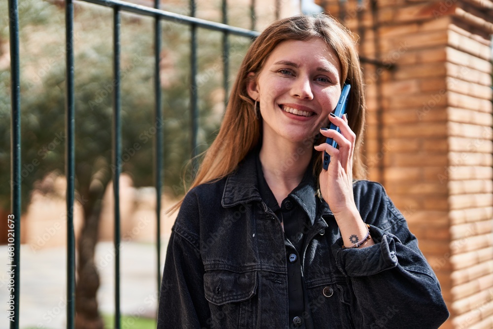 Sticker Young blonde woman smiling confident talking on the smartphone at street