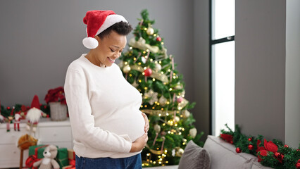 Obraz na płótnie Canvas Young pregnant woman touching belly celebrating christmas at home
