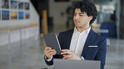 Young latin man business worker using laptop and touchpad at office